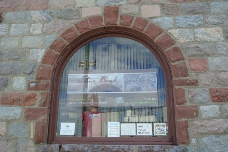 The Stone Bank's front window with a fresh coat of paint on the wooden window frame. 